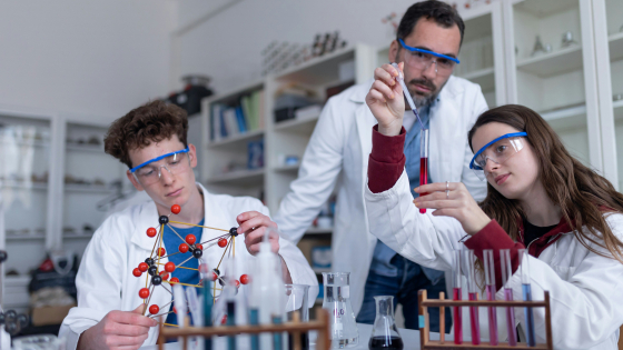 young students conducting a science experiment being overseen by an adult