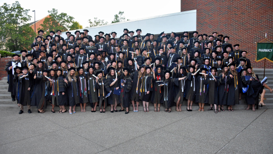 A group of graduates pose outdoors on stairs