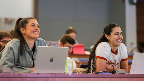 two students sitting in a classroom smiling