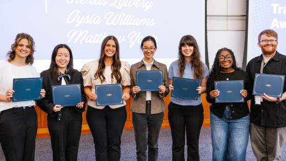 A group of students pose with their award certificates