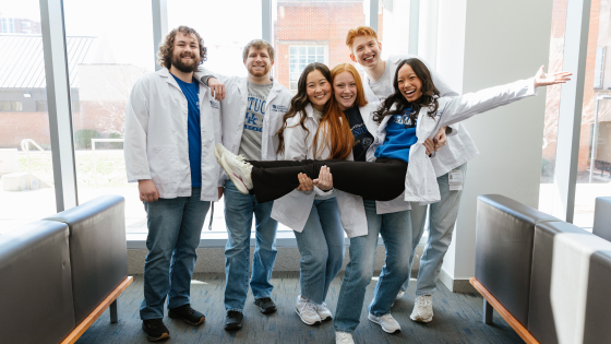 A group of students smiling and laughing in an indoor setting