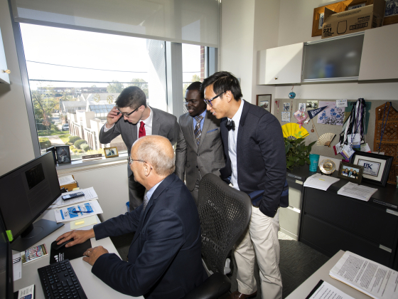 faculty member and three students looking at a computer