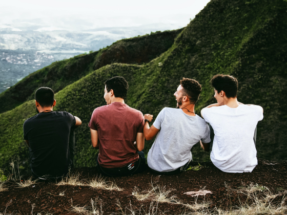 four guys overlooking a landscape viewing and laughing