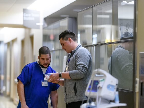 person showing a nurse about a medication in hallway of a hospital