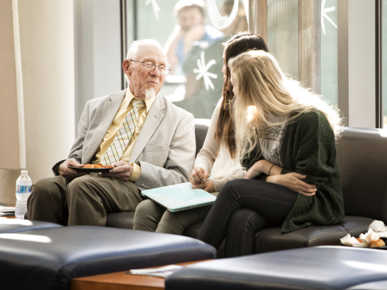 older man sitting with two students