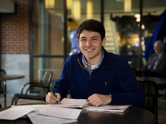 student sitting at table smiling at camera