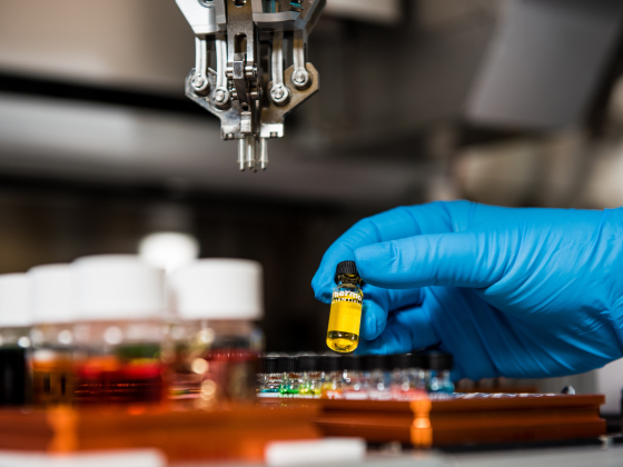 hand in blue glove holding vial