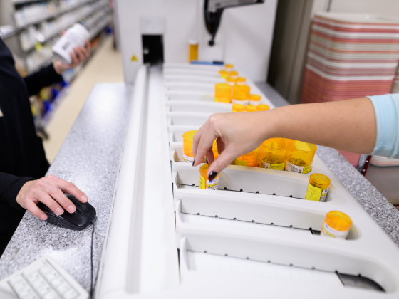 hand picking up orange medication bottle