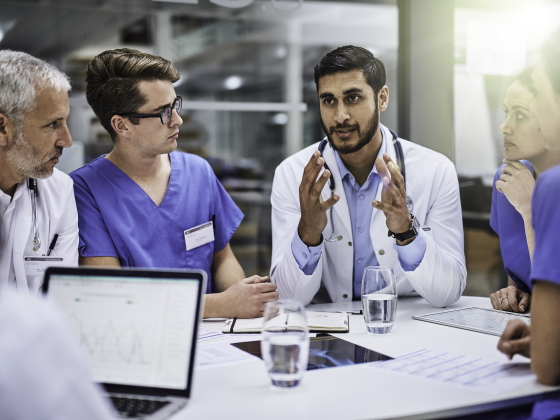 people in scrubs and white coats sitting around a table