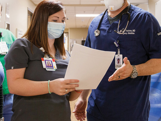 man and woman in scrubs and PPE looking at a piece of paper