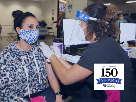 pharmacy student in scrubs and face shield vaccinating a person