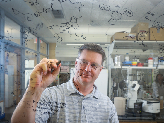 scientist writing chemical equations on glass
