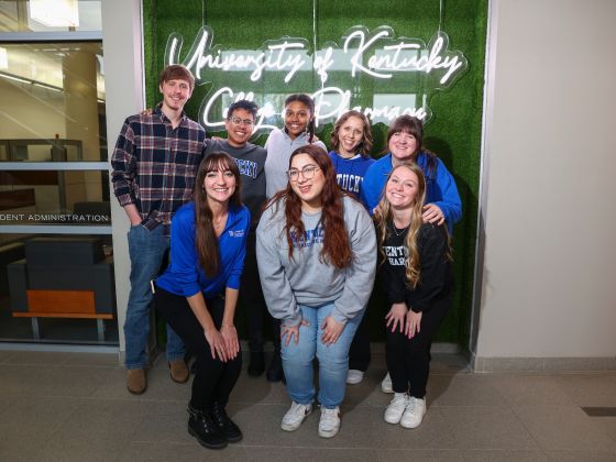 Group of students posing in front of a UKCOP light up sign