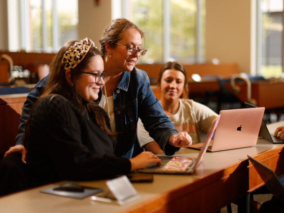 A professor pointing at a screen while two students watch