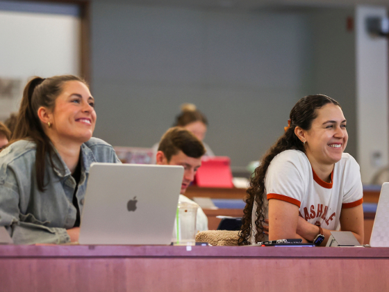 two students sitting in a classroom smiling