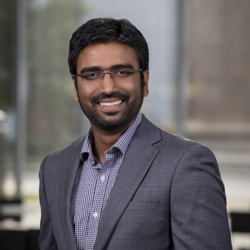 Man wearing glasses and suit jacket smiling