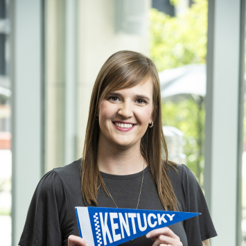 Woman smiling holding Kentucky pennant