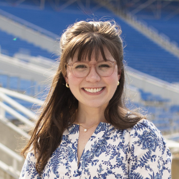 woman with long hair and glasses smiling in outdoor setting