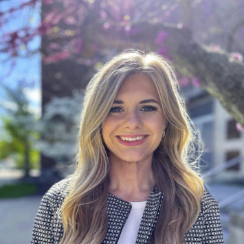 Woman with long blonde hair smiling in outdoor setting