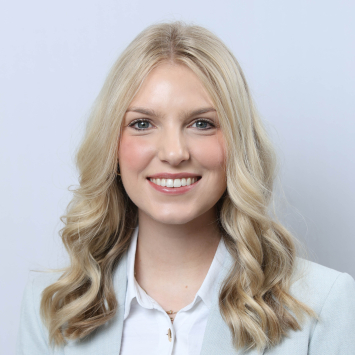 a blonde woman in professional attire against a neutral backdrop