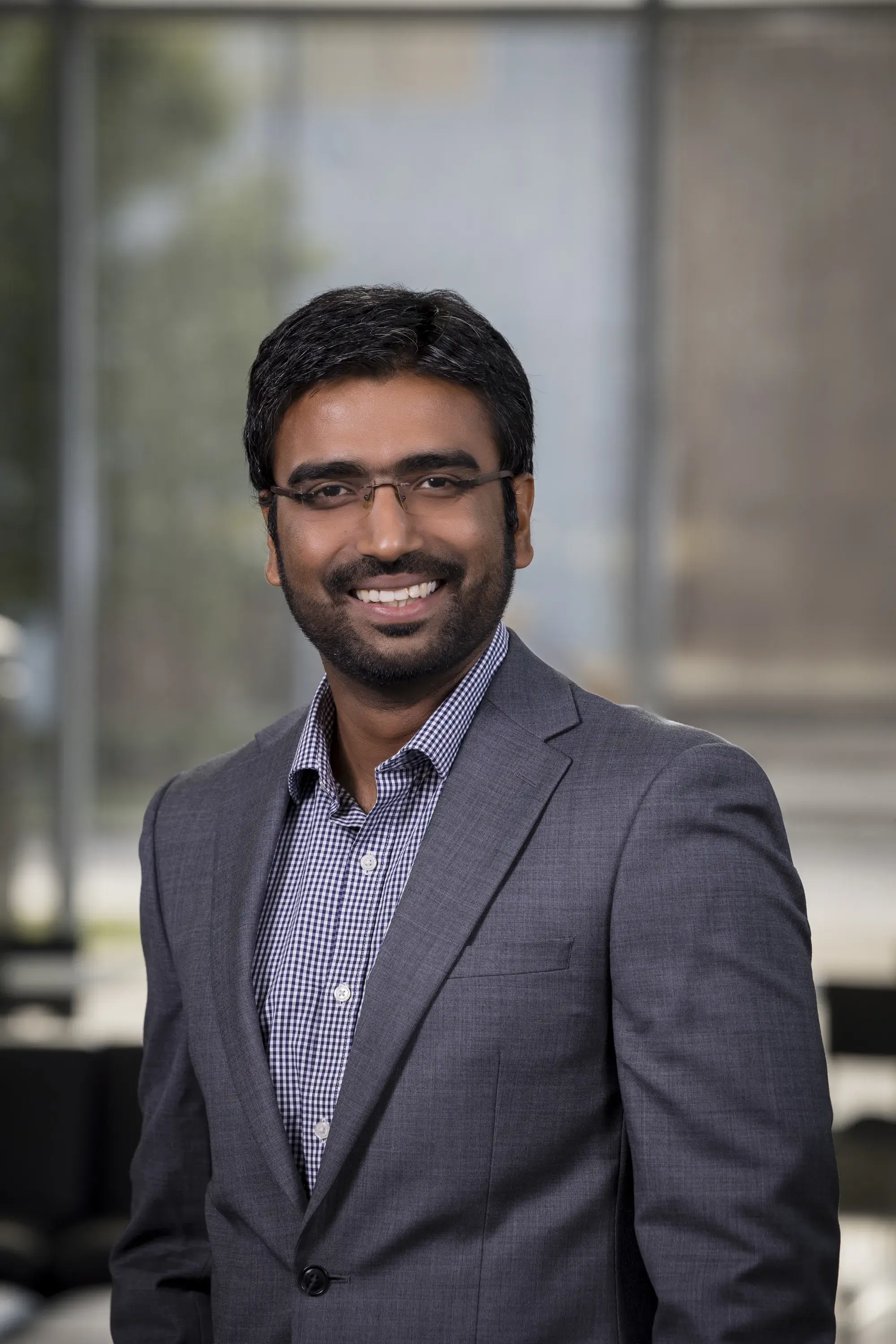 Man wearing glasses and suit jacket smiling