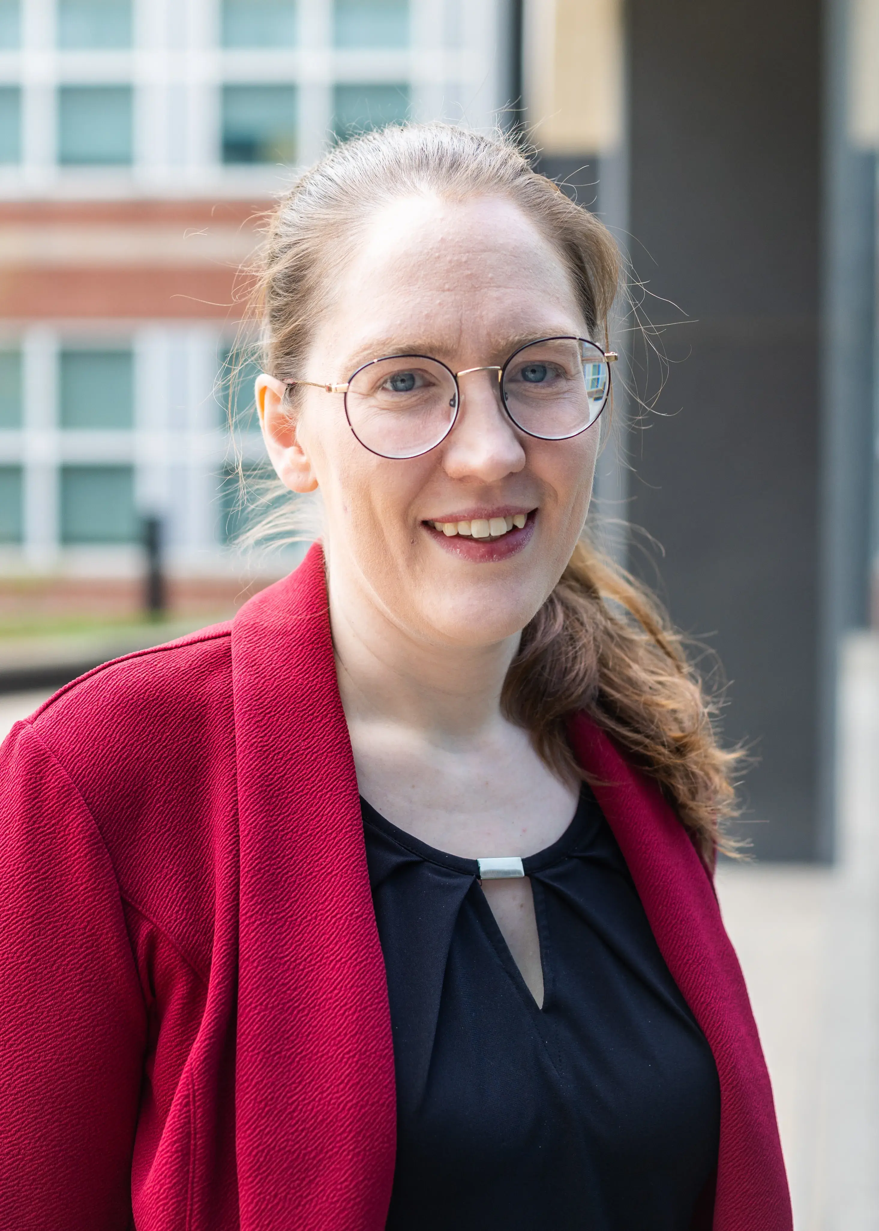 woman with hair in pony tail wearing glasses and smiling