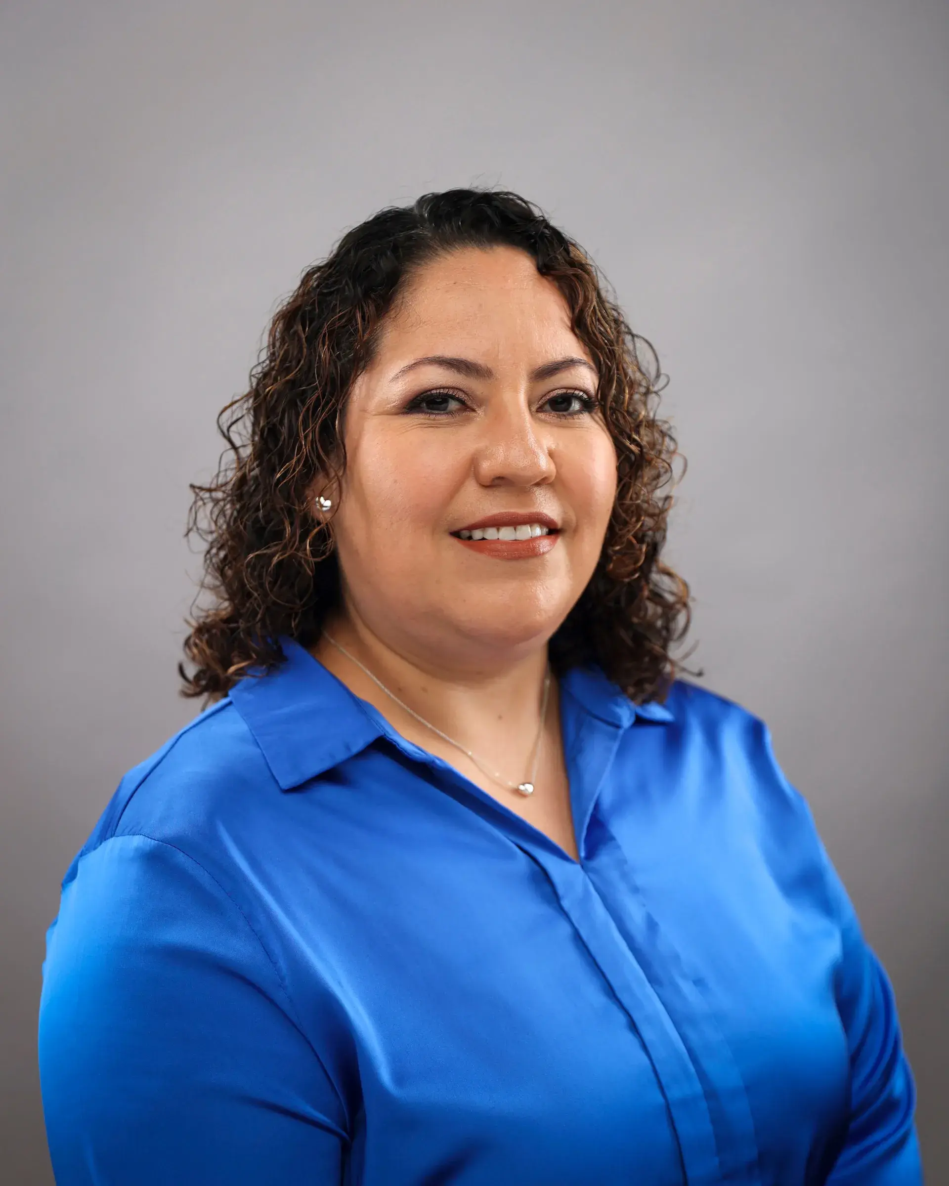 Woman with curly hair wearing blue shirt smiling
