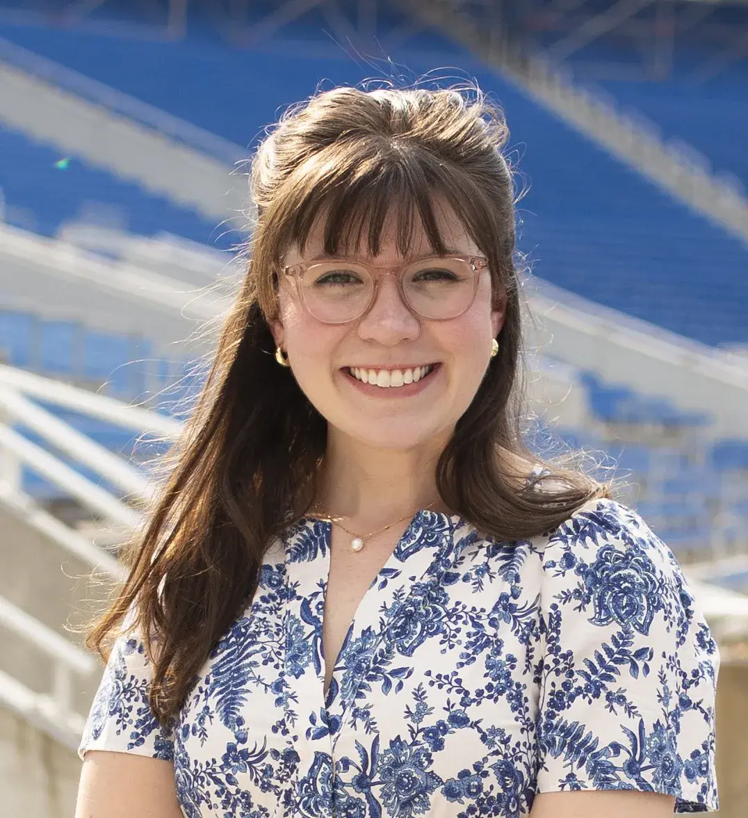 woman with long hair and glasses smiling in outdoor setting