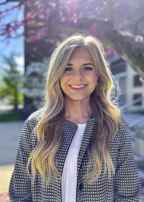 Woman with long blonde hair smiling in outdoor setting