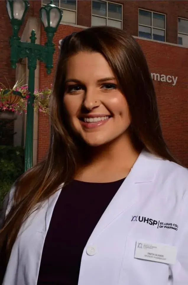 Woman with long straight hair wearing white coat smiling at camera